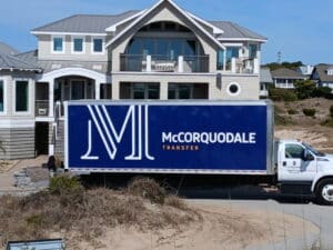 McCorquodale Transfer designer delivery truck parked outside a luxury coastal home in Wilmington, NC, providing white-glove receiving, storage, furniture delivery, and installation services for interior designers and homeowners.